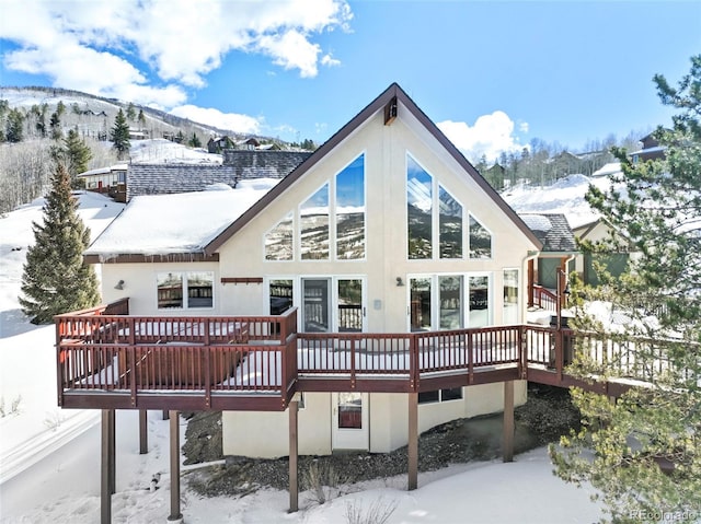 snow covered property with a deck and stucco siding