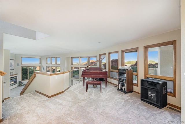 sitting room featuring carpet, baseboards, a glass covered fireplace, visible vents, and an upstairs landing