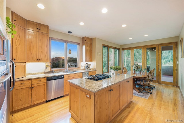 kitchen featuring a sink, light wood-style floors, gas cooktop, dishwasher, and a kitchen island