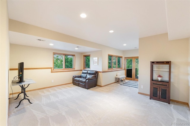 sitting room with baseboards, light carpet, visible vents, and plenty of natural light
