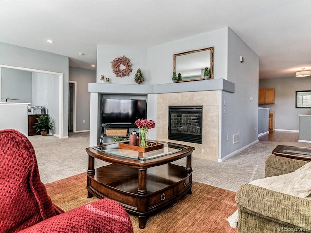 carpeted living room with a tile fireplace