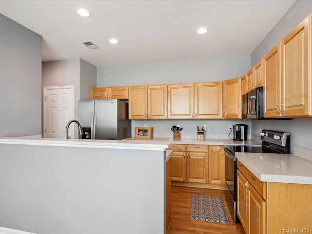 kitchen featuring light brown cabinets, stainless steel appliances, a center island, and light hardwood / wood-style flooring