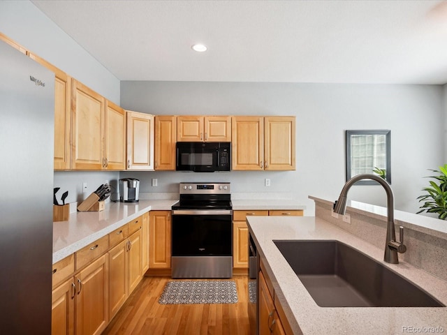 kitchen with light brown cabinets, light wood-type flooring, sink, and black appliances