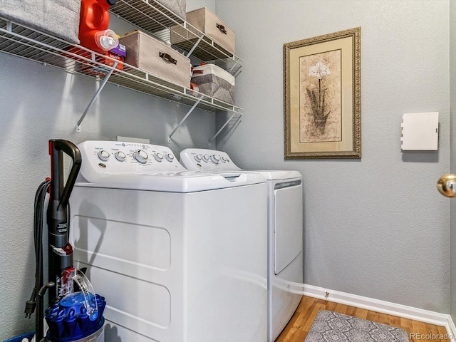 laundry area with washing machine and dryer and hardwood / wood-style flooring