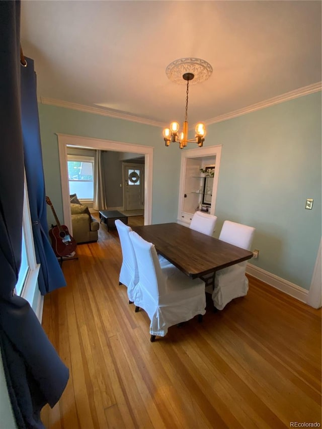 dining area featuring ornamental molding, wood-type flooring, and a chandelier