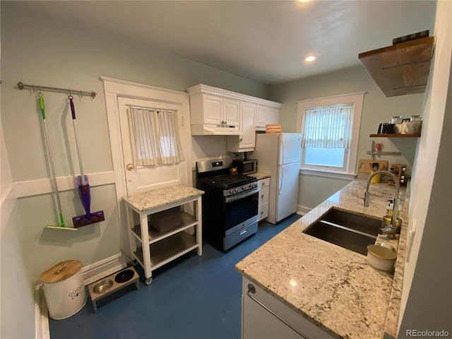 kitchen featuring white cabinets, appliances with stainless steel finishes, light stone countertops, and sink