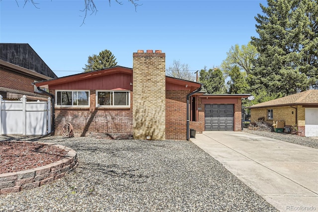 exterior space featuring fence, a chimney, brick siding, concrete driveway, and an attached garage
