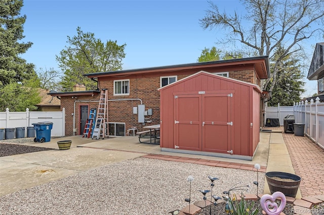 back of house featuring a storage shed, a patio area, brick siding, a fenced backyard, and an outdoor structure