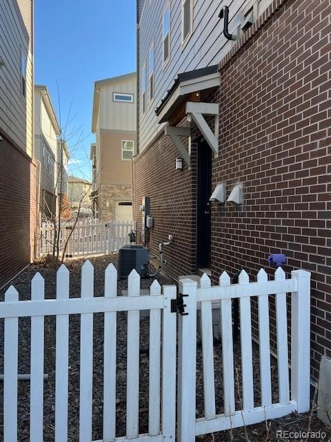 view of side of home with central air condition unit, fence, and brick siding