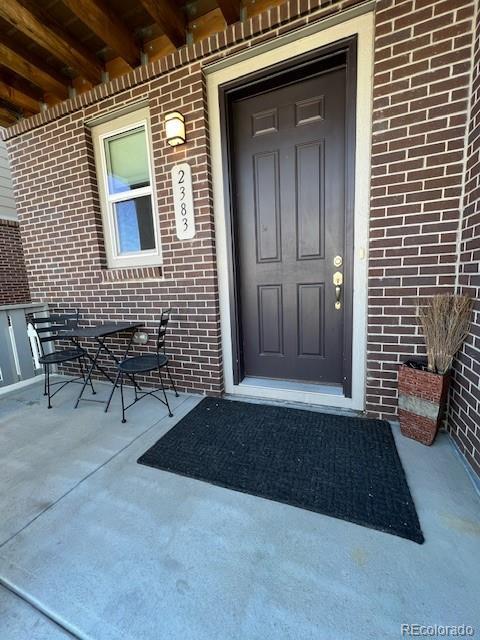 doorway to property with a porch and brick siding