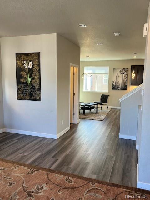 empty room featuring dark wood-type flooring, stairway, and baseboards