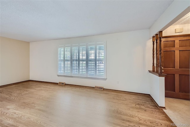 spare room with light wood-type flooring, baseboards, and visible vents