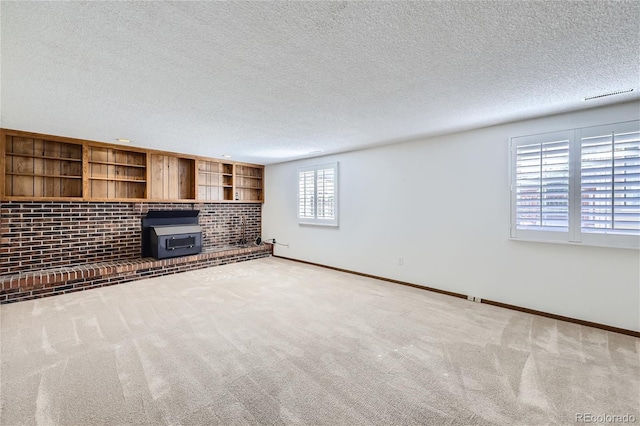 unfurnished living room with carpet, a textured ceiling, and baseboards