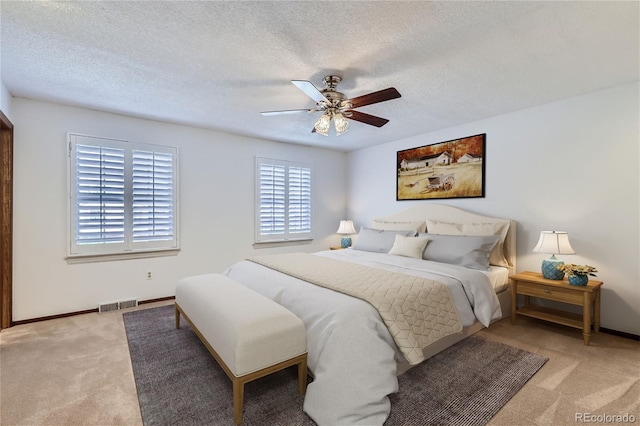 bedroom with visible vents, light colored carpet, a ceiling fan, a textured ceiling, and baseboards