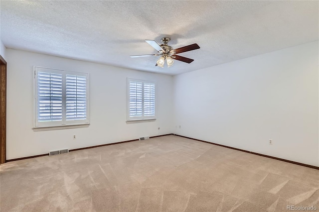 empty room featuring a textured ceiling, carpet, and visible vents