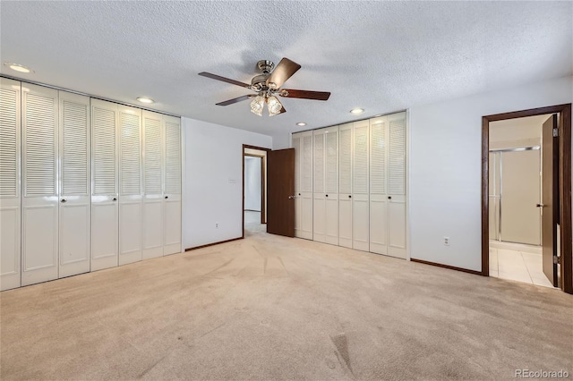 unfurnished bedroom with recessed lighting, light carpet, a textured ceiling, and two closets