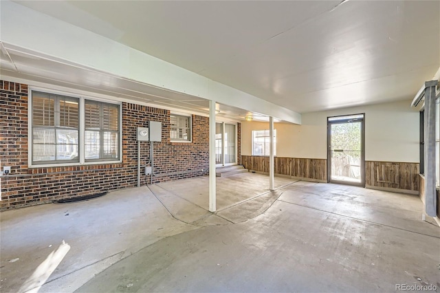 interior space with brick wall, wood walls, and wainscoting