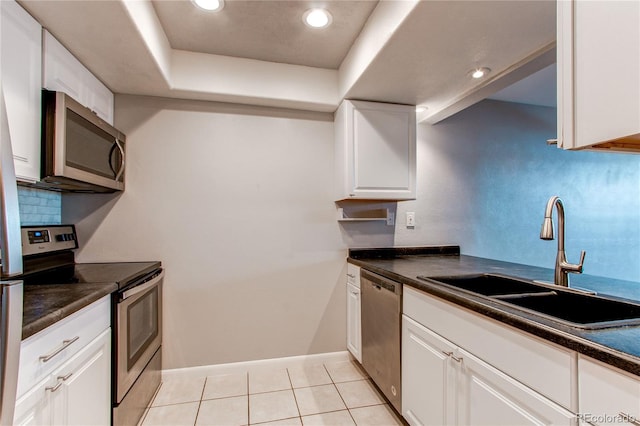 kitchen featuring tasteful backsplash, light tile patterned flooring, white cabinetry, appliances with stainless steel finishes, and sink