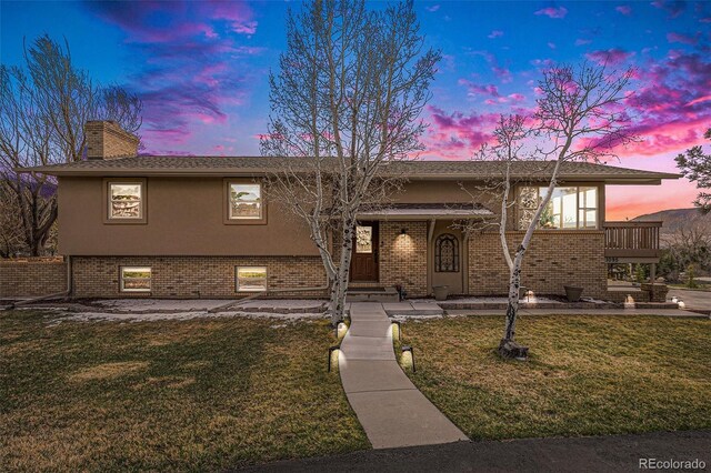 1095 Lake Woodmoor Dr, Monument, CO 80132 - bi-level home with a yard, a chimney, brick siding, and stucco siding