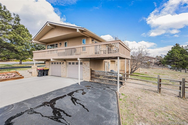 1095 Lake Woodmoor Dr, Monument, CO 80132 - view of front of house featuring driveway, brick siding, an attached garage, stucco siding, and a balcony