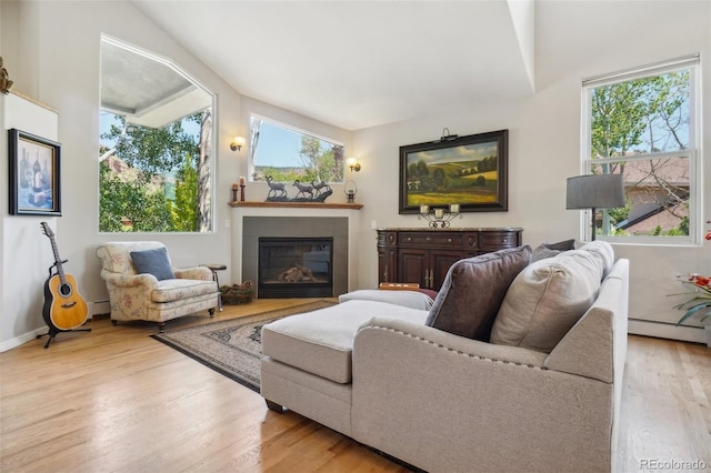 living room with light wood-style floors, a tile fireplace, baseboards, and baseboard heating