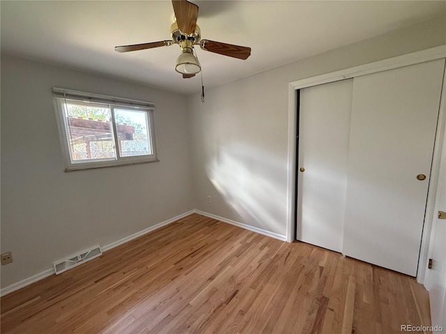 unfurnished bedroom featuring light wood-style flooring, a closet, baseboards, and ceiling fan