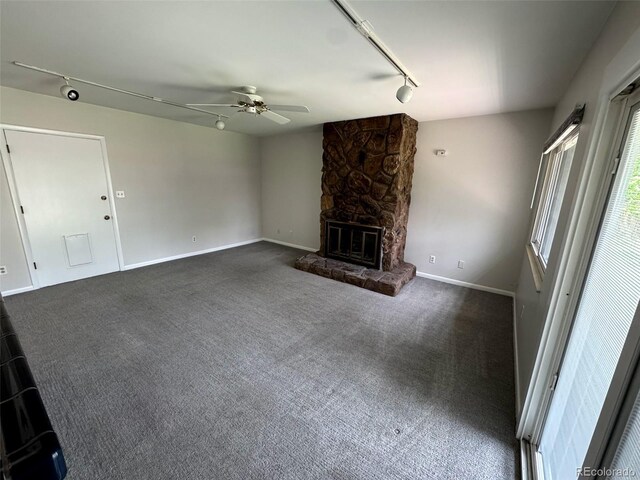 2991 S Whiting Way, Denver, CO 80231 - unfurnished living room featuring rail lighting, a ceiling fan, dark colored carpet, a stone fireplace, and baseboards