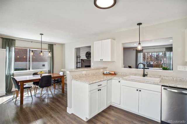 kitchen with dark wood-type flooring, stainless steel dishwasher, a sink, white cabinets, and light stone countertops