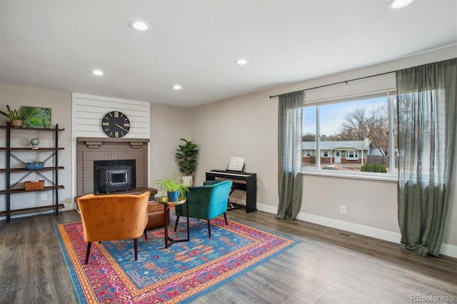 living area with recessed lighting, baseboards, visible vents, a brick fireplace, and wood finished floors