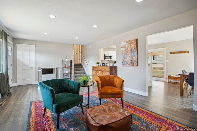 sitting room featuring dark wood-style floors, baseboards, stairs, and a wealth of natural light