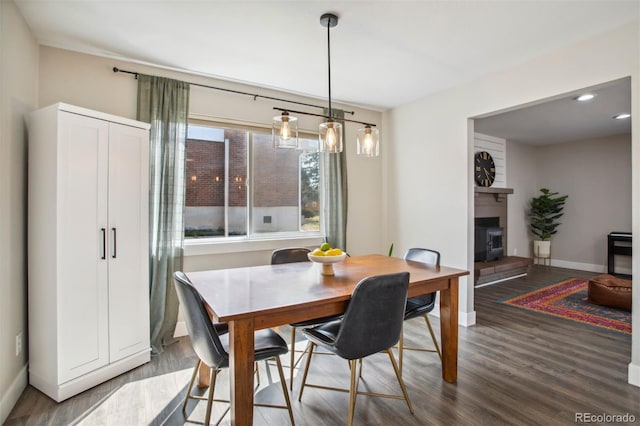 dining room with a large fireplace, baseboards, and wood finished floors