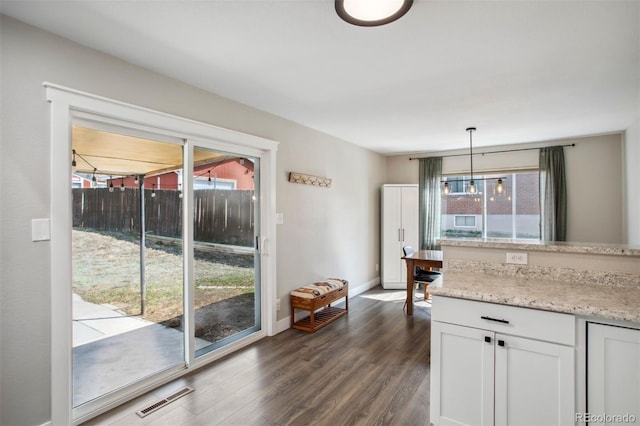 kitchen featuring dark wood-style flooring, visible vents, baseboards, white cabinetry, and hanging light fixtures