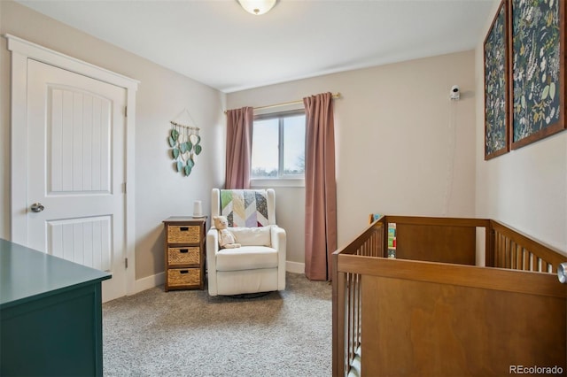 carpeted bedroom with a crib and baseboards