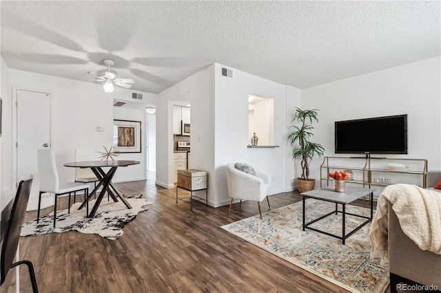 living room featuring ceiling fan, dark hardwood / wood-style floors, and a textured ceiling