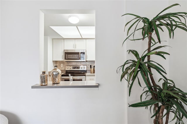 kitchen with stainless steel appliances, decorative backsplash, and white cabinets