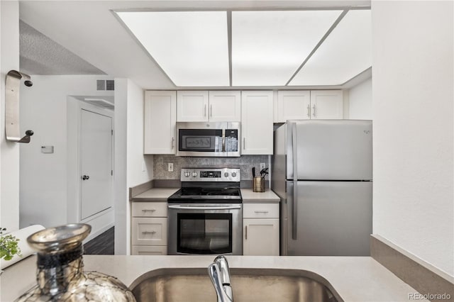 kitchen with white cabinetry, sink, decorative backsplash, and stainless steel appliances