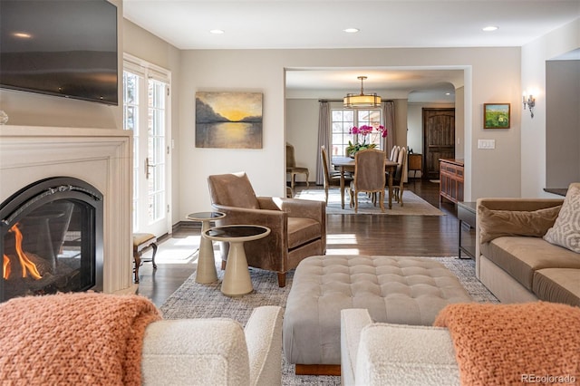 living room with a glass covered fireplace, baseboards, recessed lighting, and wood finished floors