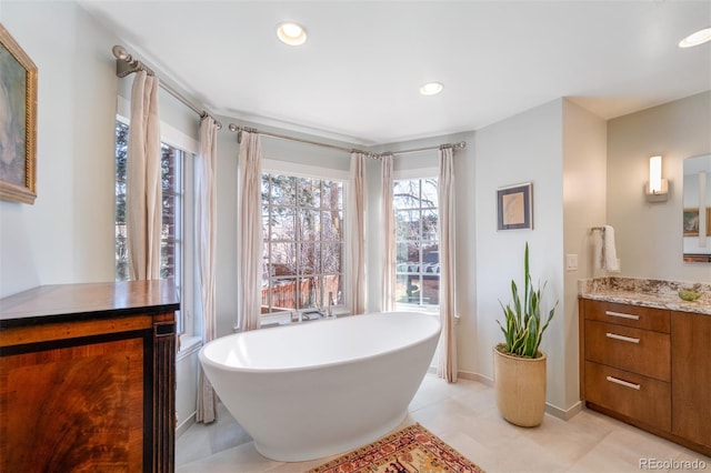 full bathroom featuring a freestanding tub, recessed lighting, baseboards, and vanity