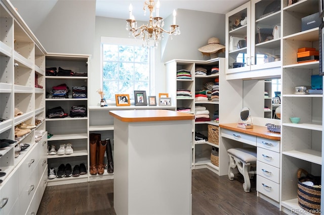 walk in closet featuring dark wood finished floors and a notable chandelier