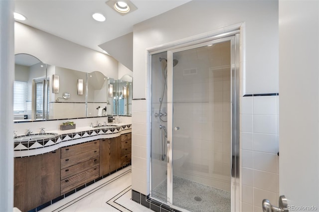 bathroom featuring a stall shower, tile patterned flooring, a sink, and double vanity