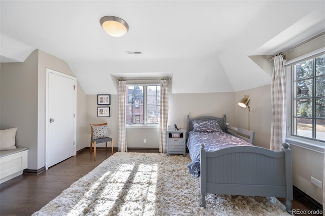 bedroom with lofted ceiling, baseboards, visible vents, and dark wood-style flooring