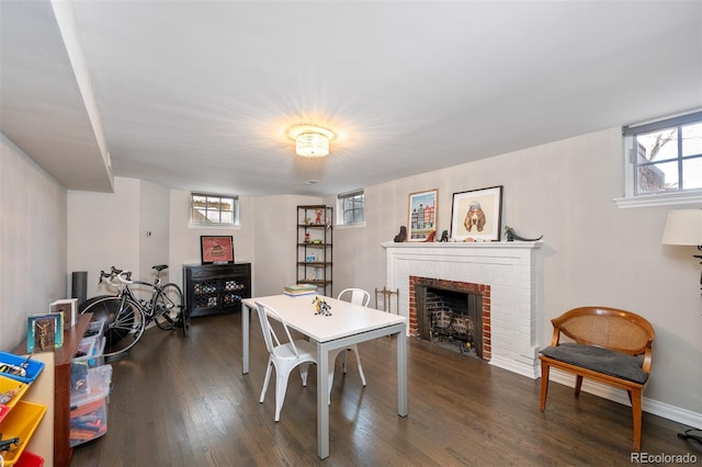 dining area with dark wood-style floors, a brick fireplace, and baseboards