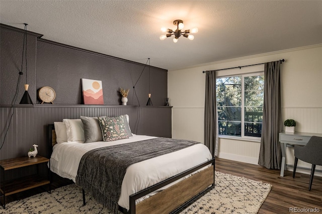 bedroom featuring crown molding, dark hardwood / wood-style floors, a textured ceiling, and a notable chandelier