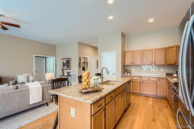 15852 Lavender Pl, Broomfield, CO 80023 - kitchen with light wood-type flooring, open floor plan, a kitchen bar, a ceiling fan, and stainless steel appliances