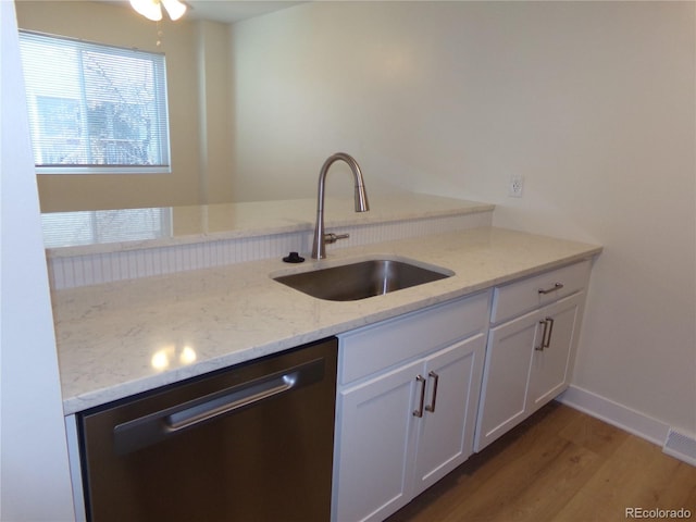 kitchen featuring hardwood / wood-style flooring, sink, stainless steel dishwasher, and light stone countertops