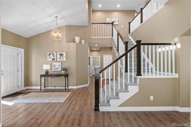 11991 Hazy Hills Dr, Parker, CO 80138 - foyer entrance featuring high vaulted ceiling, an inviting chandelier, stairway, wood finished floors, and baseboards