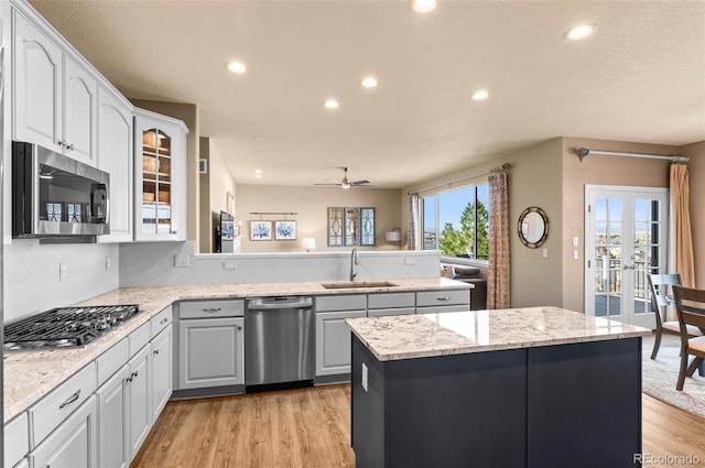 11991 Hazy Hills Dr, Parker, CO 80138 - kitchen with a peninsula, a ceiling fan, light wood-style floors, stainless steel appliances, and a sink