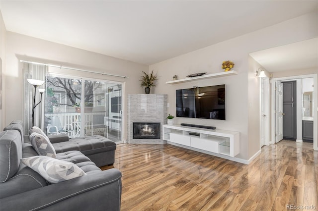 living room featuring wood finished floors, baseboards, and a tile fireplace
