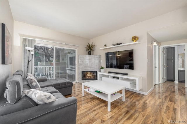 living room with wood finished floors, baseboards, and a fireplace