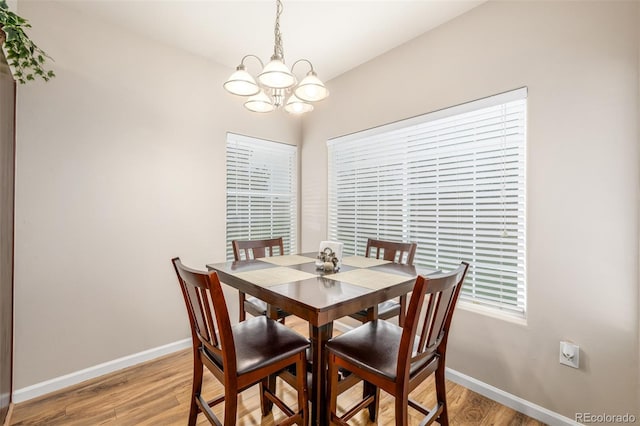 dining room featuring a chandelier, baseboards, and light wood-style floors